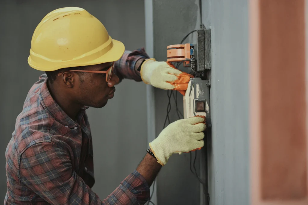 Electrician in a hard hat and gloves installing electrical wiring